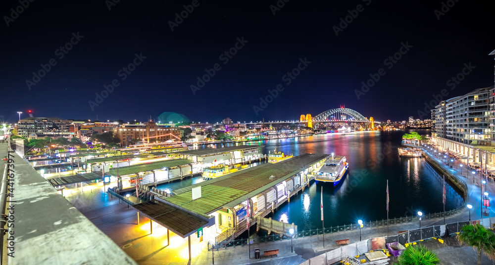 Panoramic night view of Sydney Harbour and City Skyline of circular quay the bridge  nsw Australia.  bright neon lights reflecting off the water