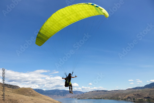 Adventurous Caucasian Adult Woman learning to Fly on a Paraglider around the mountains. Savona, British Columbia, Canada.