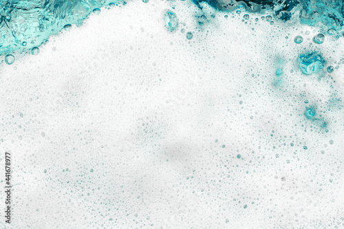 White foam blue water background closeup, sea or ocean foam wave pattern, froth bubbles texture, soap spume backdrop, cleaning soap sud, lather surface, soapy detergent, laundry, foamy bathtub, shower