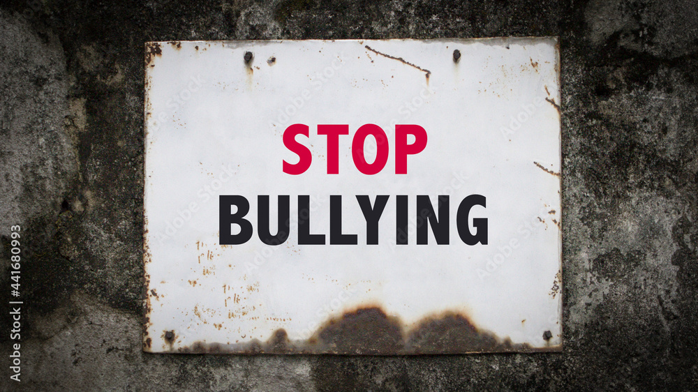 Stop Bullying, words on a grunge metal board on wall.