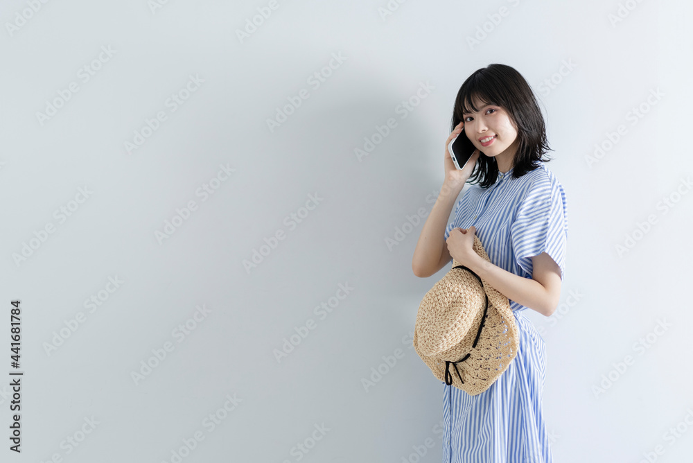 スマートフォンを使う麦わら帽子の女性