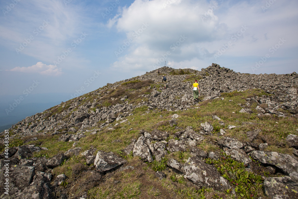 The top of the rocky mountain Golets. Tourists climb the rocky slope to the top of the mountain.