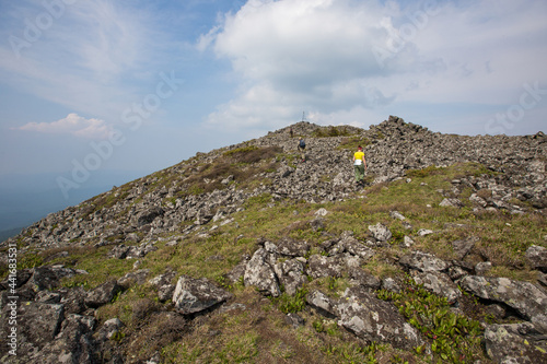 The top of the rocky mountain Golets. Tourists climb the rocky slope to the top of the mountain.