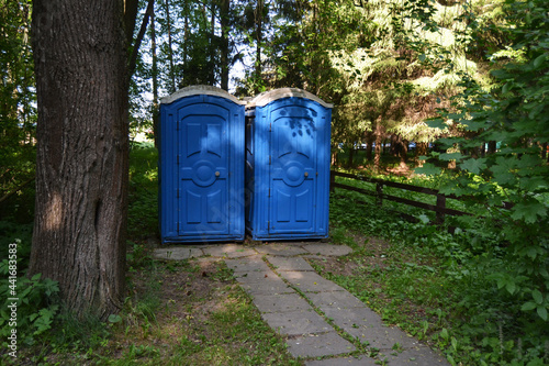 Portable Toilets By Road Against Trees photo