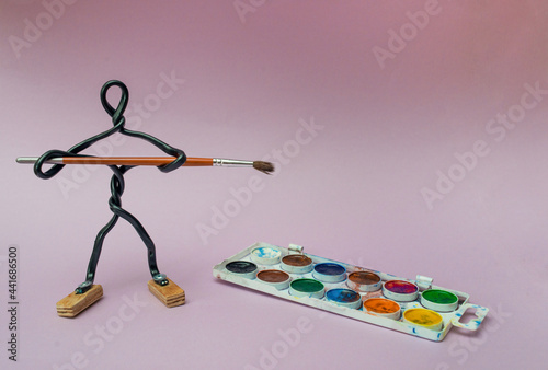 Creativity and art concept. Man made of wire with paintbrush in his hands.