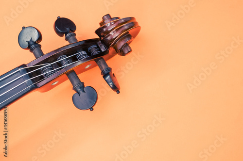 Pegbox of a violin on orange background with a copy space photo