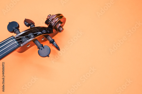 Pegbox of a violin on orange background with a copy space photo