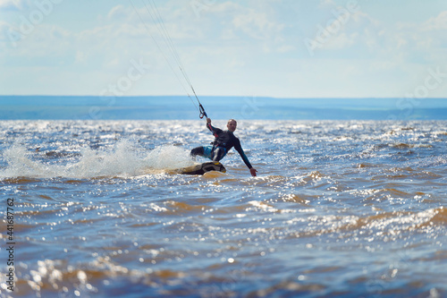 Kiteboarder surfing waves with kiteboard on a sunny summer day.