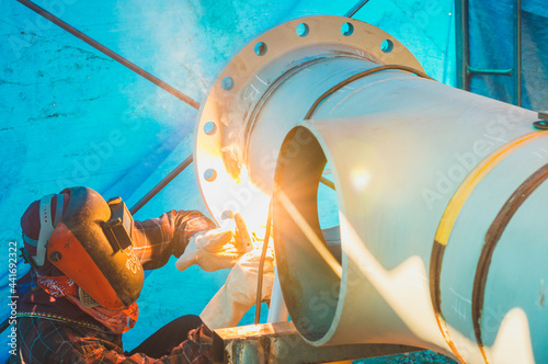 Welder wearing protective clothing for welding industrial construction oil and gas  at construction site .man welds at the factory.