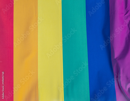 Rainbow flag in sunshine against blue sky