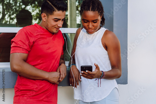 young latin and african american girl listening to music on a mobile phone