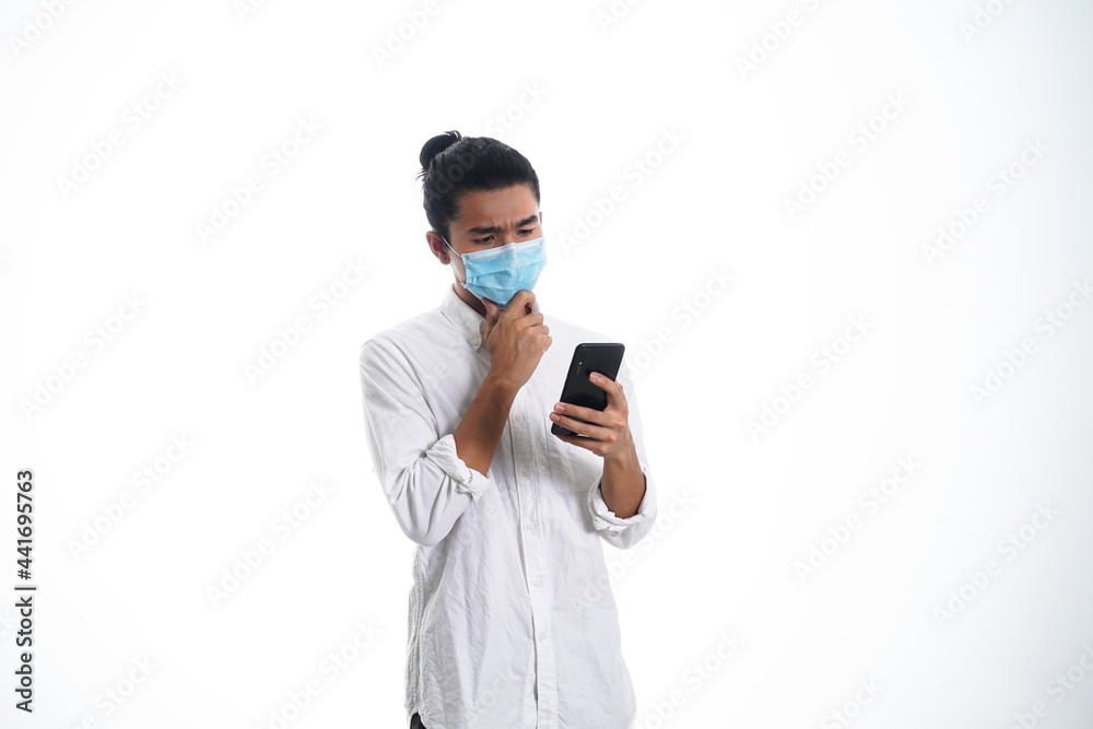 Covid19, the concept of health care and medicine. A young man reading a news on his phone in a face mask, supporting social distance Covid19, the concept of health care and medicine. A young man reading a news on his phone in a face mask, supporting social distance