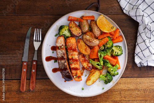 Homemade Grilled Salmon Steak with Broccoli, Potatoes, Carrots in a plate on a wooden table