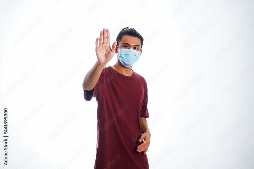 Covid19, the concept of health care and medicine. A young man standing in a face mask with hand gesture Covid19, the concept of health care and medicine. A young man standing in a face mask with hand gesture