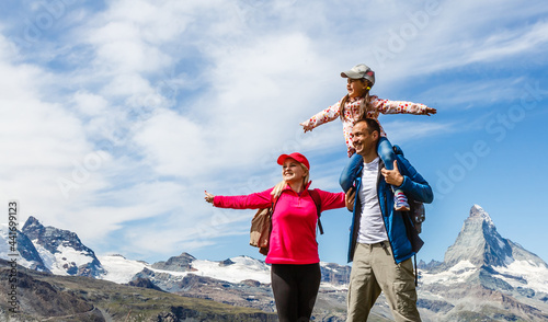 Obraz na plátně Happy family with little child doing trekking on switzerland mountain in summer time
