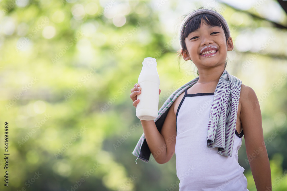 Naklejka premium Cute asian little child girl is drinking a milk, soft focus
