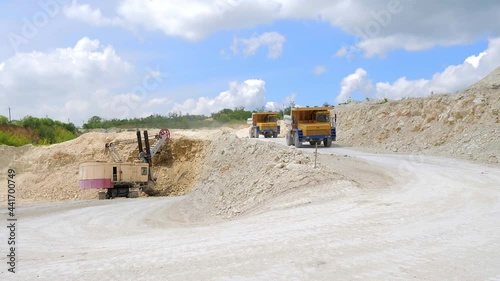 An orange dump truck is driving through a sand quarry, mining equipment. Mining industry. Heavy industry