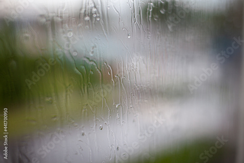 Rainy day through the window on sky and city buildings background