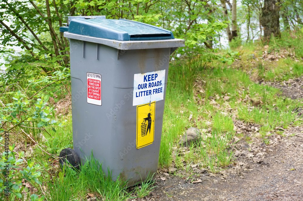 Keep roads litter free sign at roadside on wheelie bin Keep roads litter free sign at roadside on wheelie bin