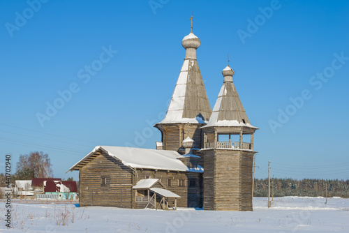 Ancient wooden church John Chrysostom with a bell tower in the Saunino village of Kargopol district on a sunny February day. Arkhangelsk region, Russia photo