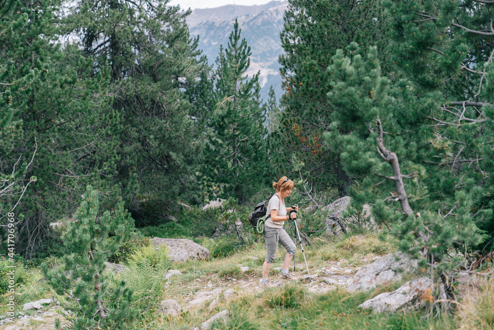 Active woman walking with poles on stony hill slope Active woman walking with poles on stony hill slope