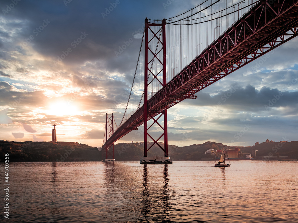 Ponte 25 de Abril Bridge in Lisbon during Sunset with ship and jesus monument, cloudy sky portugal Ponte 25 de Abril Bridge in Lisbon during Sunset with ship and jesus monument, cloudy sky portugal