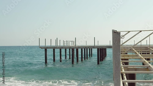 Dismantled cafe on the pier of a Turkish resort in the Mediterranean. Consequences of the covid-19 pandemic. Sea waves. Seascape