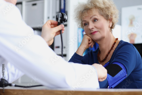 Physician therapist measures blood pressure of elderly woman