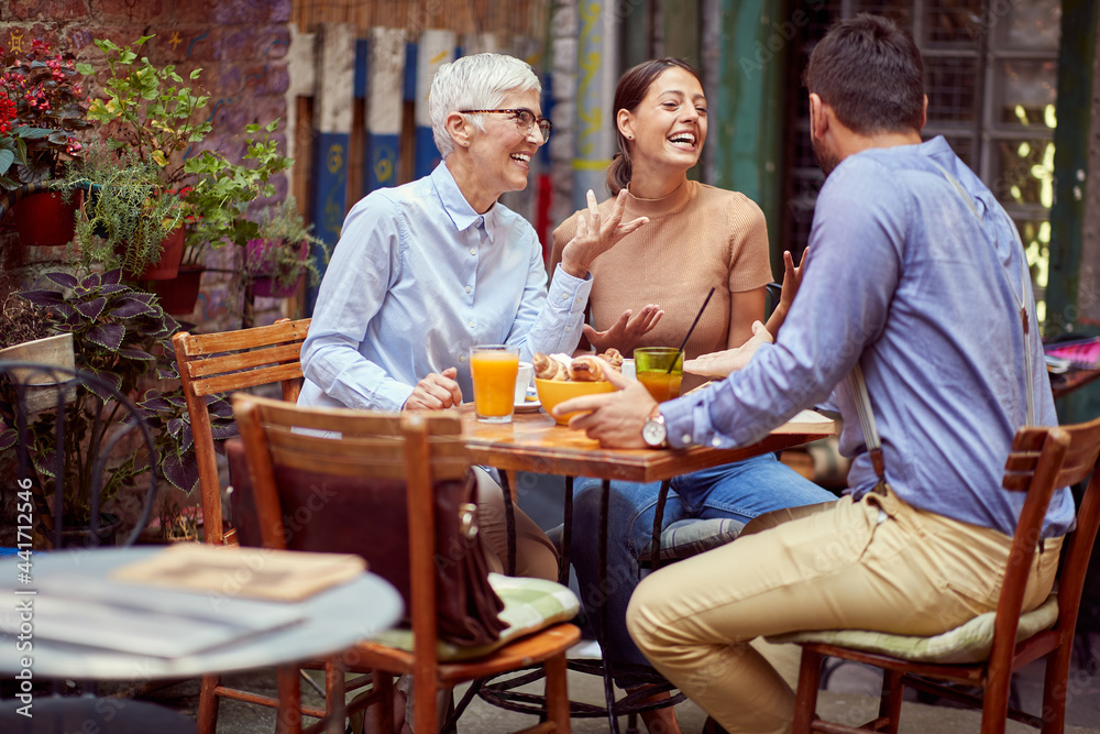 © luckybusiness - elderly woman having conversation with young adult female and her boyfriend, smiling, having breakfast together in outdoor cafe. © luckybusiness - elderly woman having conversation with young adult female and her boyfriend, smiling, having breakfast together in outdoor cafe.