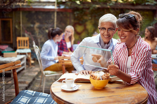 young adult woman showing something on transparent notepad to senior female