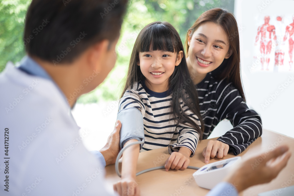 Asian doctor examining a girl body by stethoscope at hospital .Hospital and Insurance Concept. Measuring blood pressure and checking pulse Asian doctor examining a girl body by stethoscope at hospital .Hospital and Insurance Concept. Measuring blood pressure and checking pulse