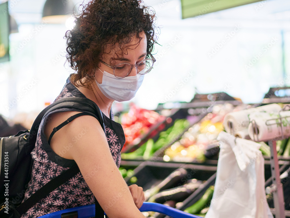 A woman wears a face mask while shopping in a supermarket