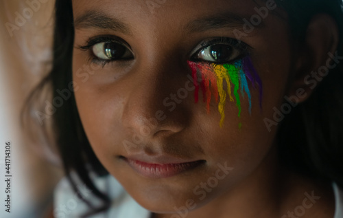 Extreme close up face of a beautiful dark-skinned young girl with rainbow-colored eye makeup | concept, proud, confident member of the LGBT community