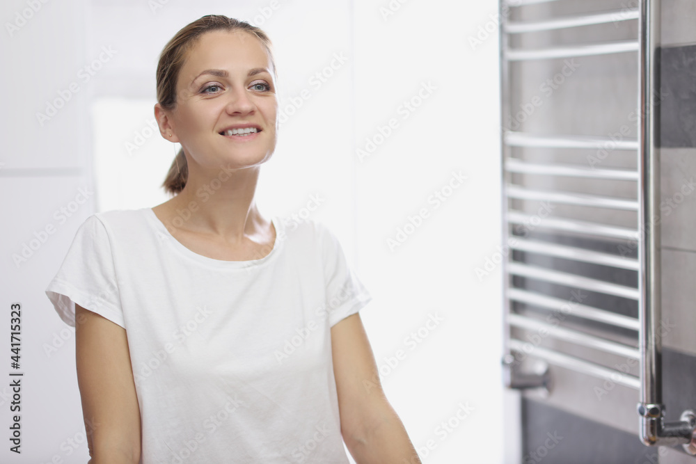 Portrait of young smiling woman looking at herself in bathroom mirror