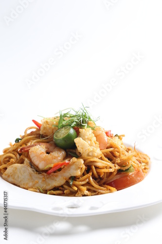 stir fried spicy chilli noodle mamak mee goreng with mixed seafood fish, prawn, squid, meat and lime asian halal menu