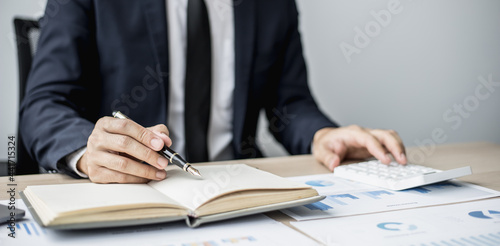 Businessman takes notes on a topic that examines information from finance documents to bring to department and partnership meetings, preparing monthly meeting information. Financial management concept