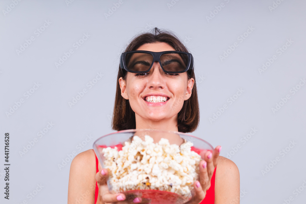 Beautiful woman on gray background in 3d cinema glasses with popcorn, cheerful happy positive emotions Beautiful woman on gray background in 3d cinema glasses with popcorn, cheerful happy positive emotions
