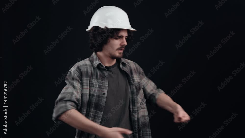 The ambitious worker with the white helmet of the engineer pulls the rope with all his might. Isolated on black background. The concept of life. People's emotions. 4k portrait The ambitious worker with the white helmet of the engineer pulls the rope with all his might. Isolated on black background. The concept of life. People's emotions. 4k portrait