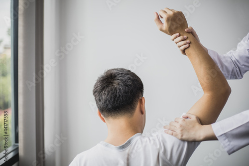 Fotografija A professional physiotherapist is doing stretching for a patient, the patient has muscle dysfunction due to hard work, most often an office worker who has problems sitting for long periods of time