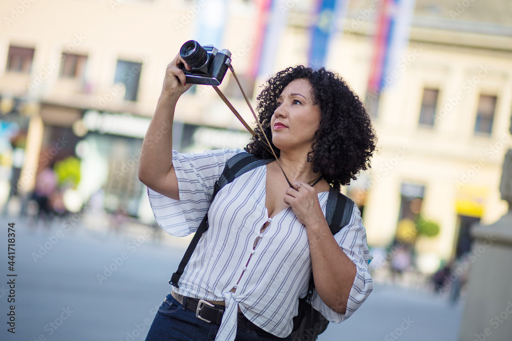 Woman standing on street and taking photo.
