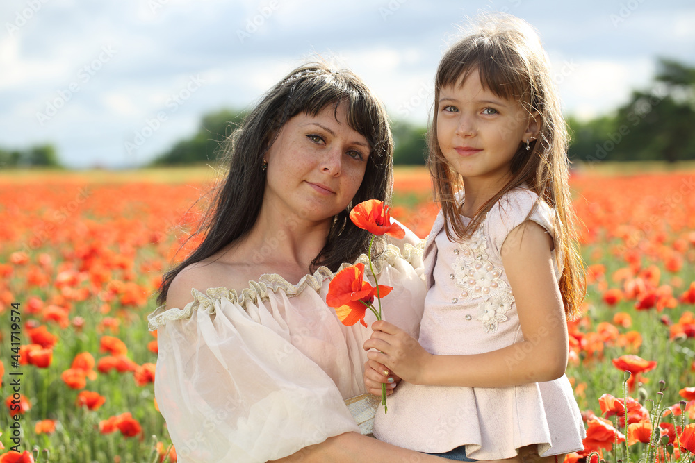 Mother and daughter are walking in a beautiful field of poppies Mother and daughter are walking in a beautiful field of poppies