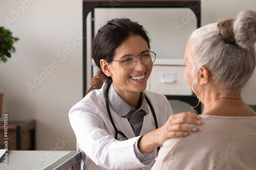 Close up of smiling young female nurse comfort caress old woman patient show good medical service in private clinic. Happy woman doctor support mature lady client. Geriatrics healthcare concept.