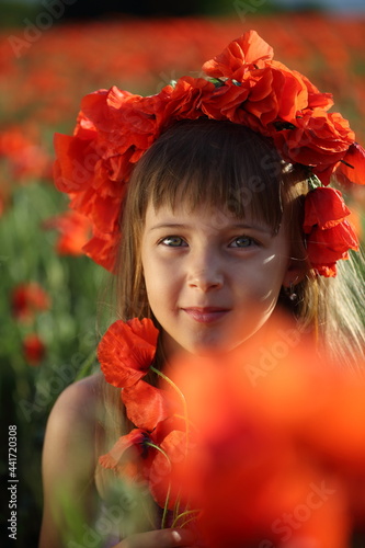 Little girl walks in a beautiful field of poppies