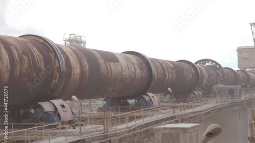 An industrial cement processing facility. Rotating furnace equipment at the factory, working in an electric furnace. Rotary kiln (RKF). Roasting rotary kiln at a cement plant. photo