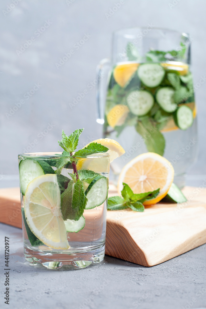 Fototapeta premium Water with cucumber, lime and mint on a gray rustic background. In a glass decanter