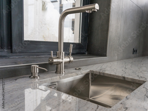 Fotografie Stainless steel undermount kitchen sink and faucet with light marble countertop