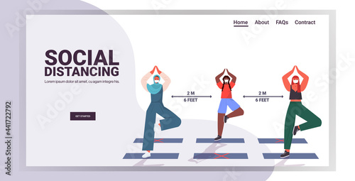mix race girls in masks doing yoga exercises keeping distance to prevent coronavirus social distancing
