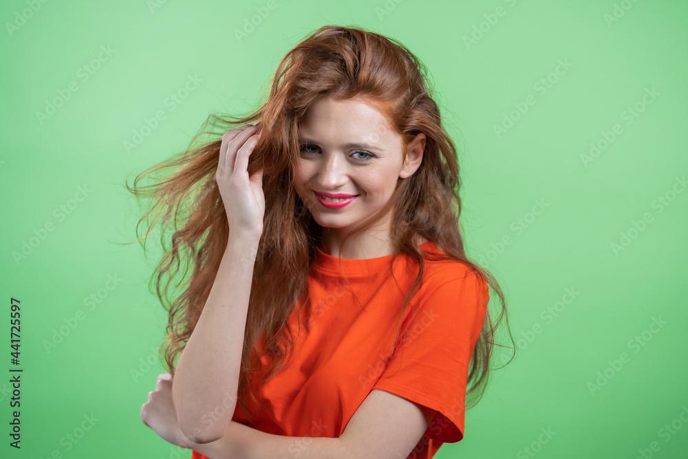 Young woman with red hairstyle looking to camera, flirting. Beautiful model girl on green studio background. Young woman with red hairstyle looking to camera, flirting. Beautiful model girl on green studio background.