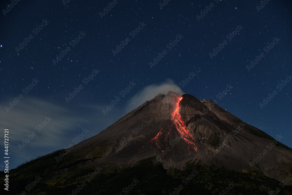 Mount Merapi erupts with high intensity at night during a full moon, the slide of material avalanches reaches 2700 meters - obrazy, fototapety, plakaty 