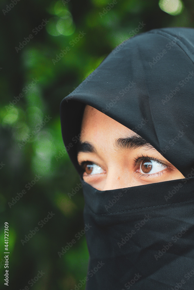 Closeup of beautiful woman face covered with hijab. Perfect shiny eyes of a Muslim girl. Young niqab girl portrait with the background.